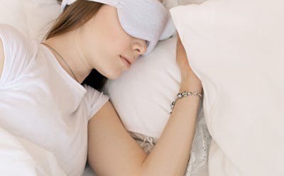 Personne endormie portant un masque de sommeil dans un lit