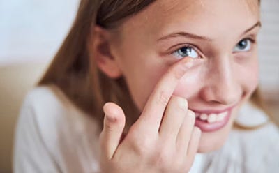 Personne plaçant une lentille de contact sur son œil avec le bout du doigt